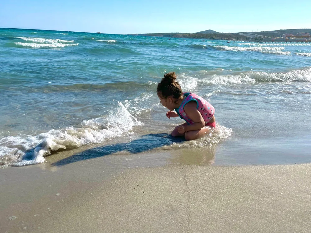 Tekke Plajına gelen küçük kız su dalgalarıyla oynuyor