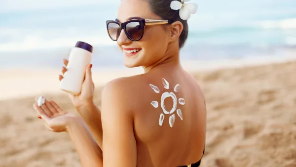 Bronz tenli kadın sırtına güneş kremiyle güneş resmi çizmiş
