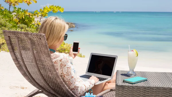Tatilde laptopuyla çalışan bir sarışın kadın