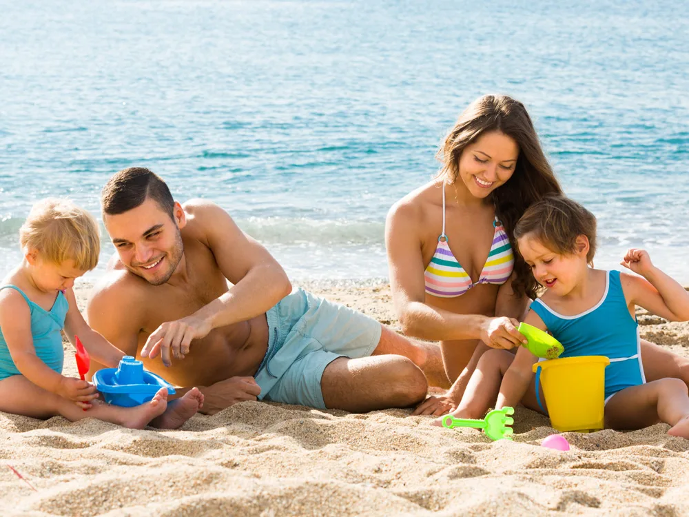 Aile ile yapılan 3 günlük tatil planından kumda çocuklarıyla oynayan evli çift