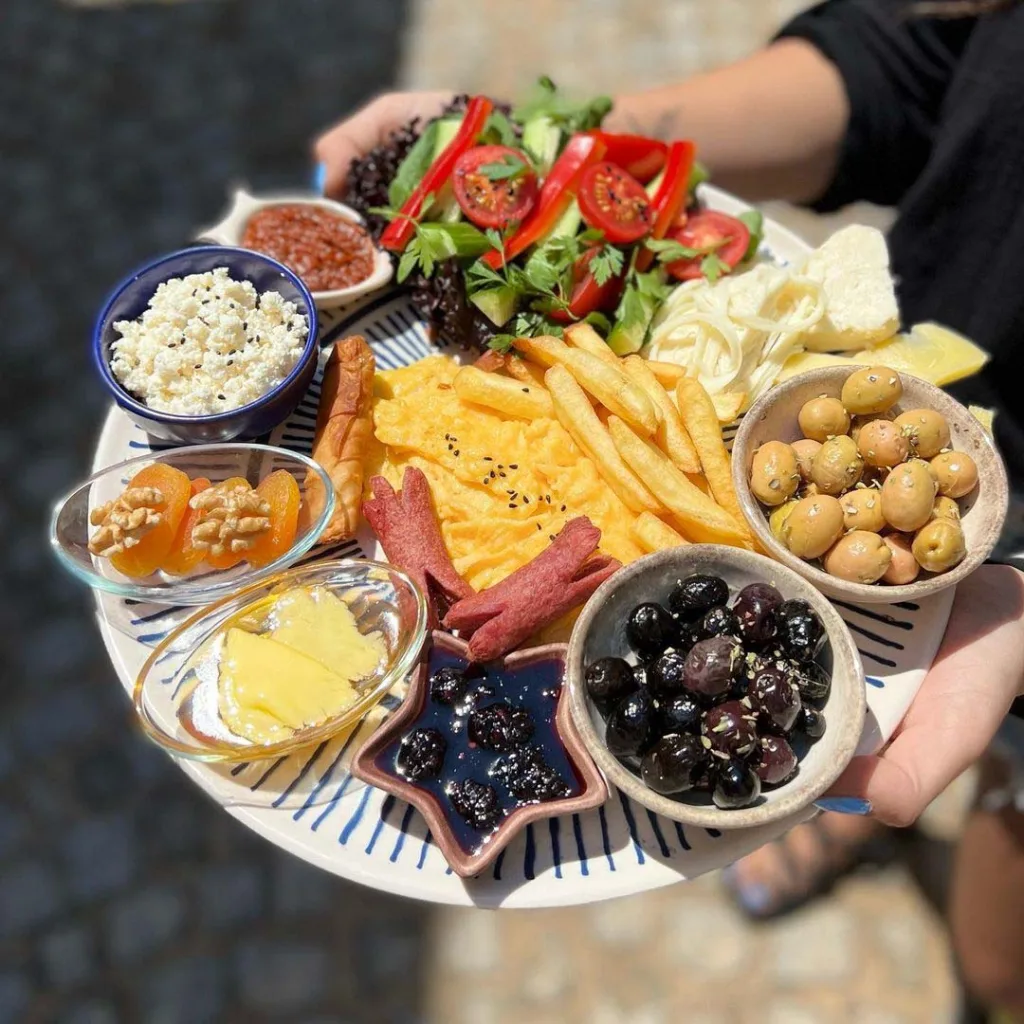 Lawaga Alaçatı'da sosis, patates, zeytin, salata ve peynirlerden oluşan kahvaltı tabağı