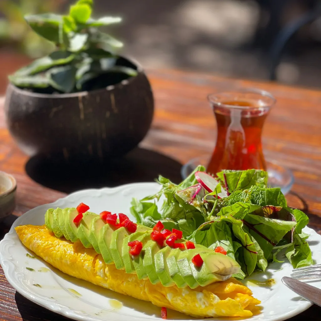 kahvaltı mekanları arasından Nann Alaçatı'da lezzetli omlet üzerinde sağlıklı avokadolar ve bol yeşillikli salata