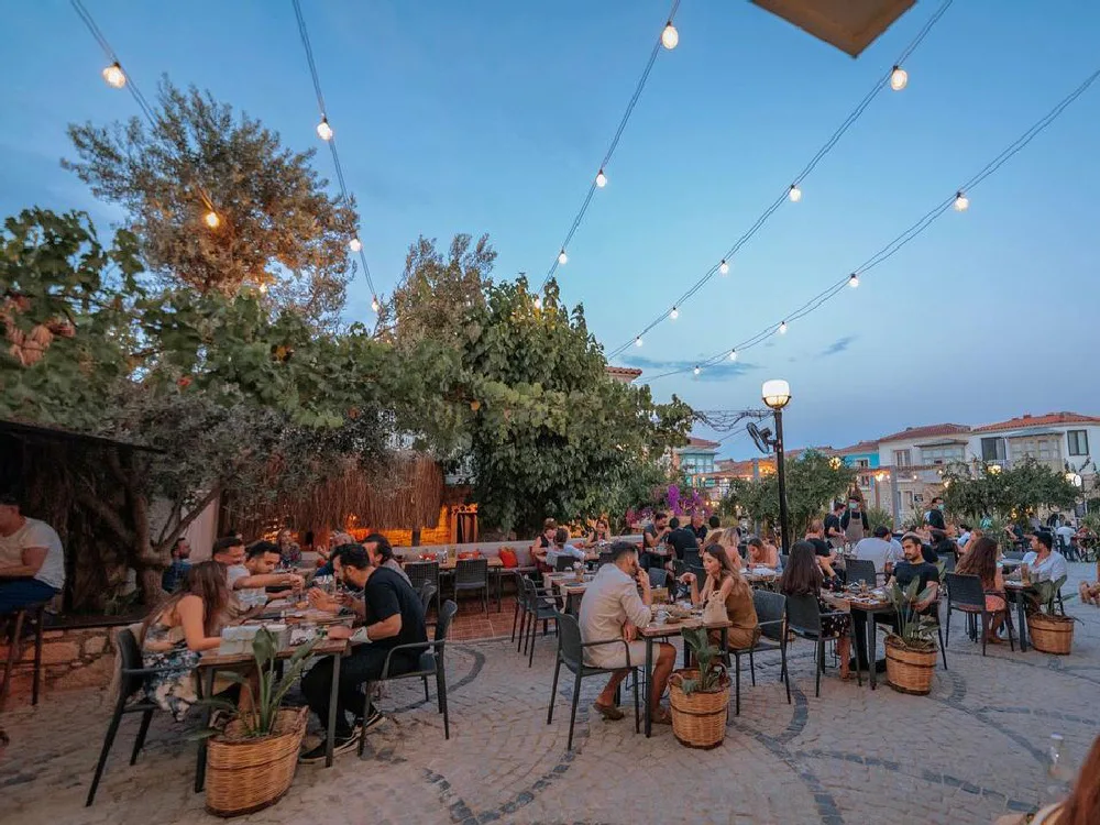 Restoranlar listesinden Ortaya Alaçatı'nın ağaçlarla süslenmiş bahçesi ve masalar