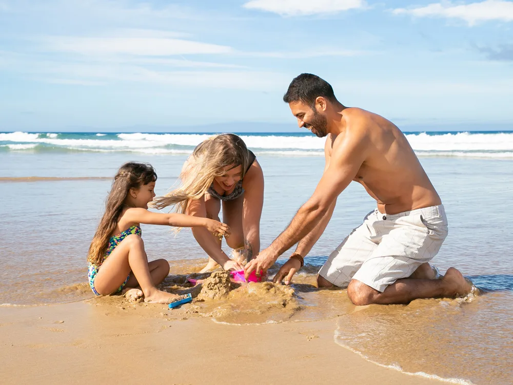 Aile ile yapılan 3 günlük Alaçatı tatil planından kumda çocuklarıyla oynayan evli çift