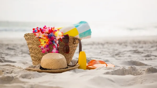 sahilde duran hasır çanta, içindeki eşyalar ve şapka