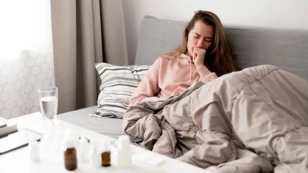 Hasta kadın yatağında yatıyor ve öksürüyor, masanın üzerinde kimyasal içeren ilaçlar var