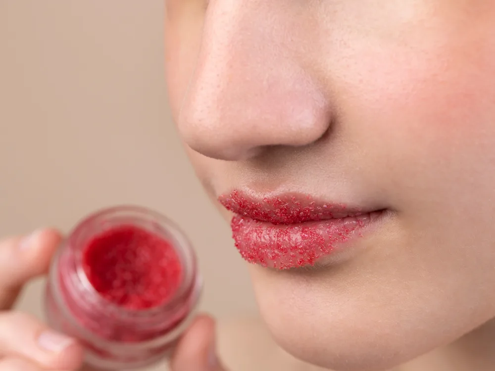 Evde hazırladığı kırmızı dudak balmını dudaklarına süren kadının yakından resmi
