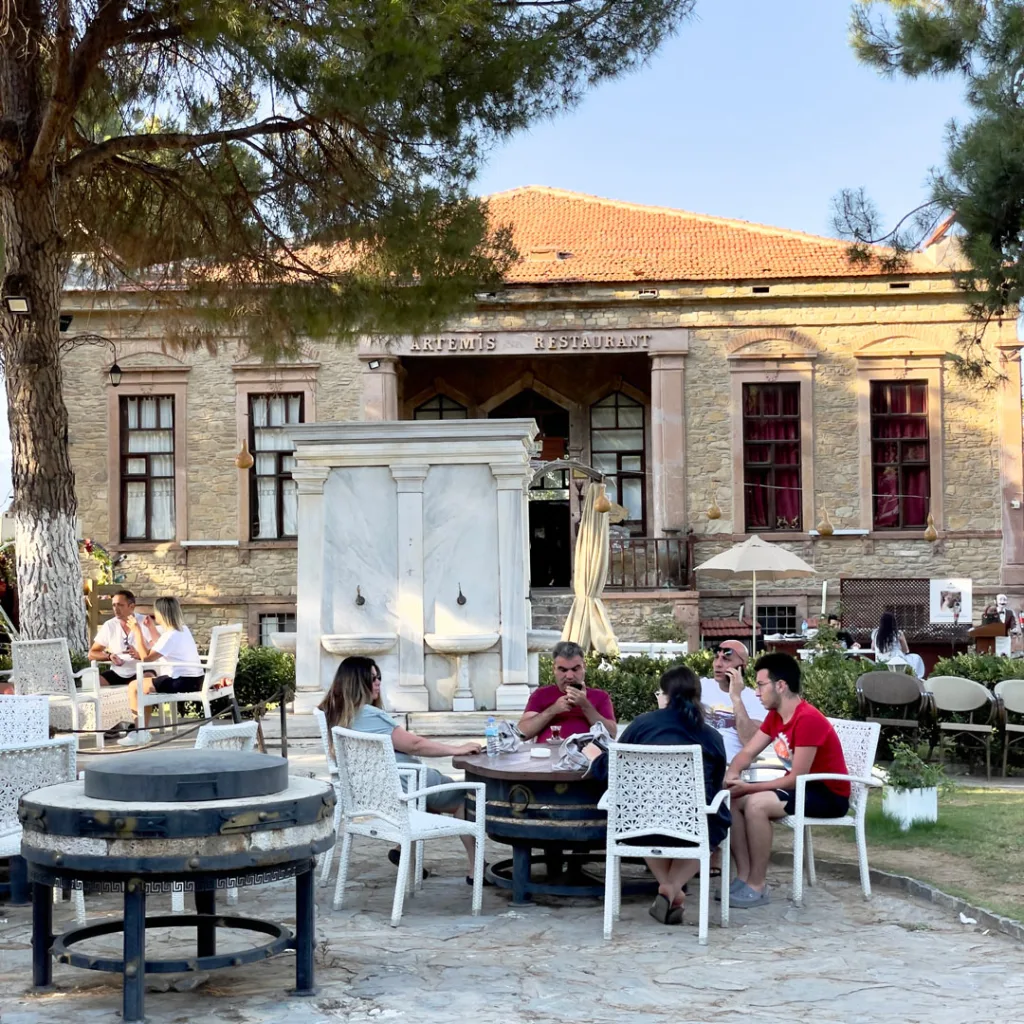 Tarihi Artemis Restaurant ve önünde yemek yiyen insanlar