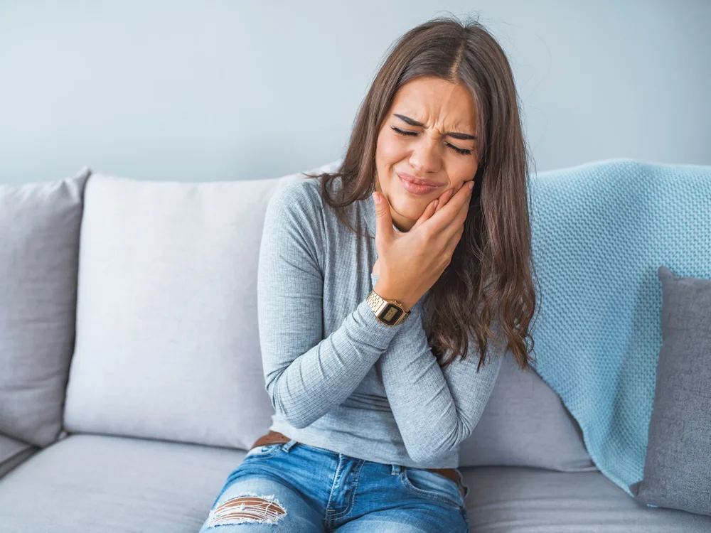 diş ağrısı ile mücadele etmeye çalışan kadının acı dolu yüz ifadesş