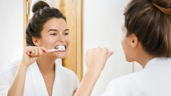 Ayna karşısında dişlerini fırçalayan beyaz dişli kadın
