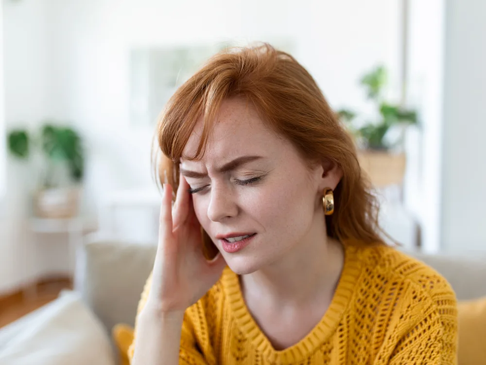 migren problemi çeken kadın başı ağrıdığı için acıyla kafasını tutuyor