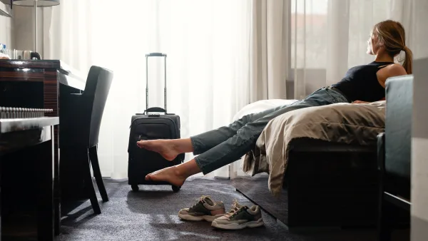 otel odasında ayaklarını uzatarak dinlenmeye çalışan genç kadın