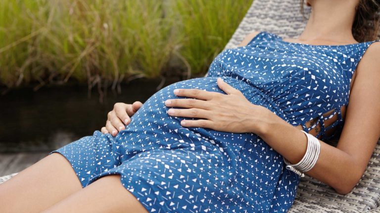Hamilelikte tatil yapan kadın şezlongda uzanıyor.