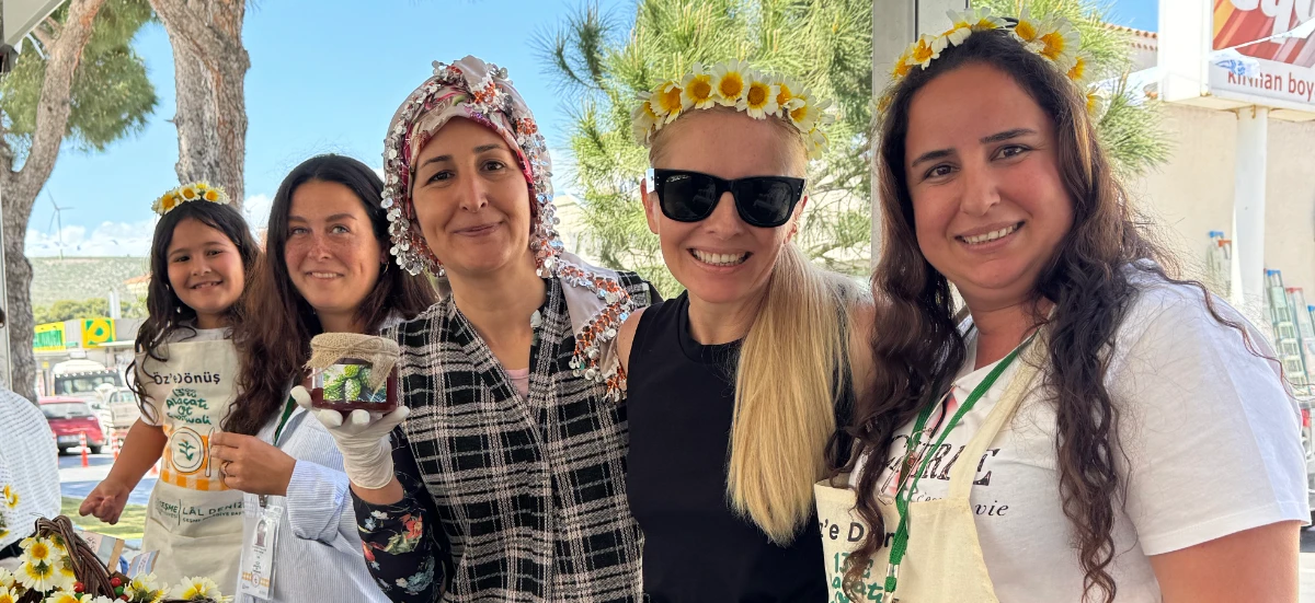 15. Alacati Ot Festivali Banner shows 4 women and one girl at the festival selling honey.